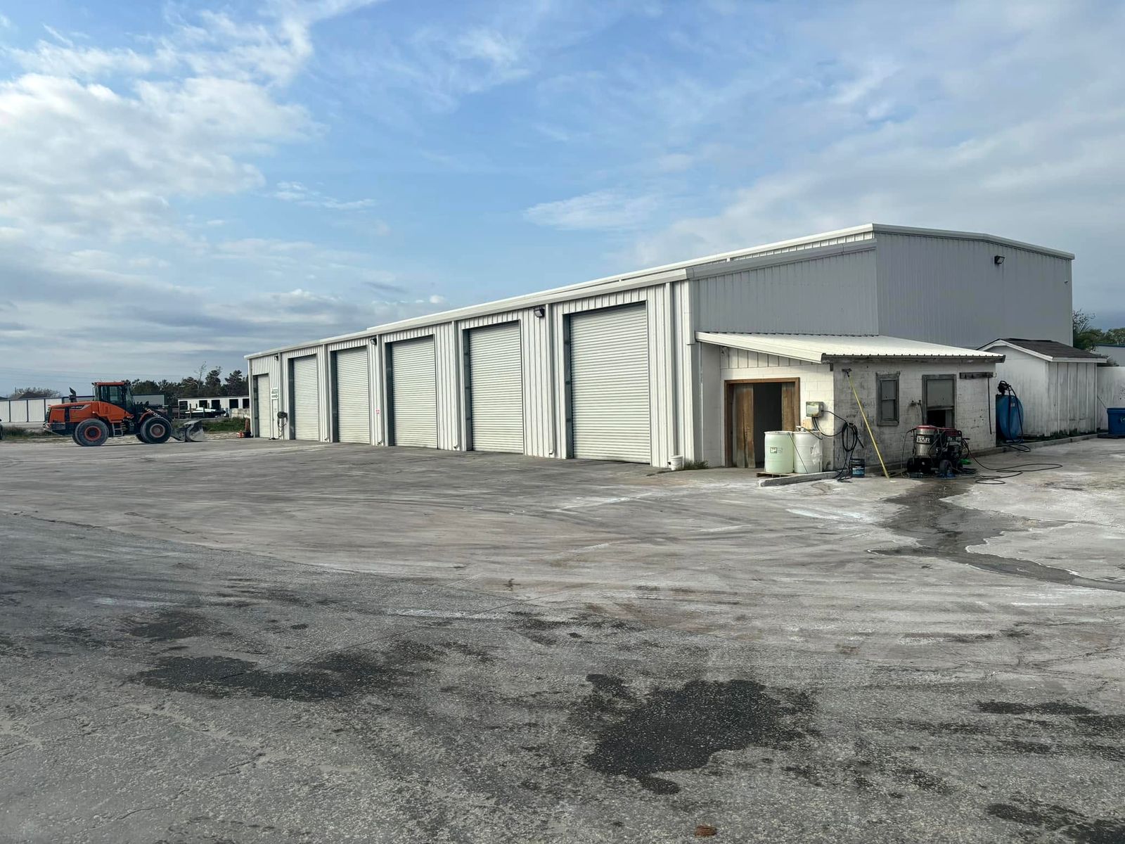 White metal shop building with four roll-up doors on a wide paved yard in Melbourne